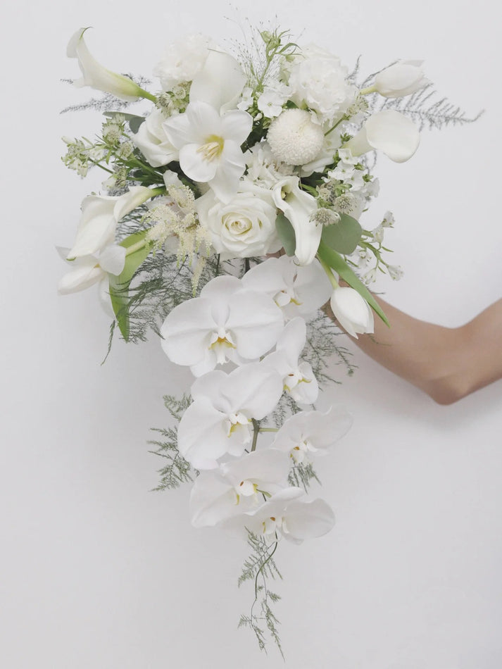 Cascading bridal bouquet featuring roses, tulips, phalaenopsis and foliage